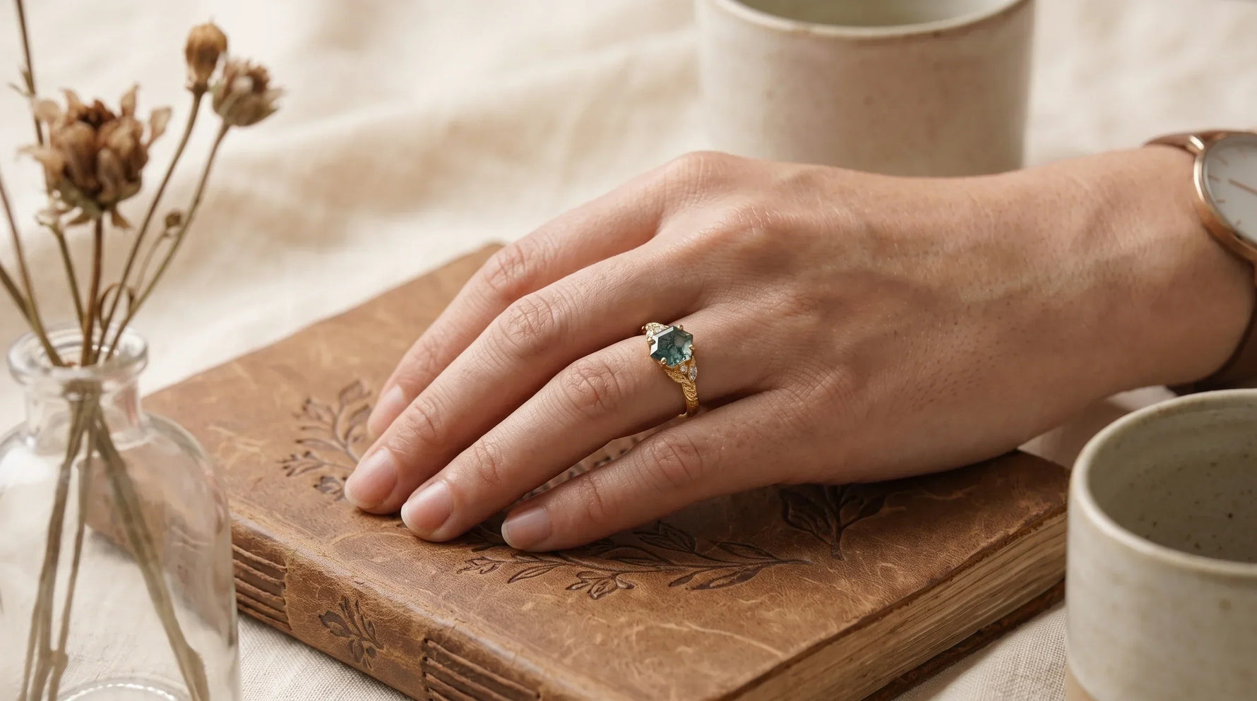 A hand wearing a moss agate ring with natural green inclusions in an everyday setting